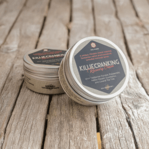 Two containers of Killiecranking Recovery Cream rest on a wooden surface. The label highlights ingredients like Kunzea, Peppermint, Bushy Yate, and Coastal Tea Tree. Trail Science Recovery Cream